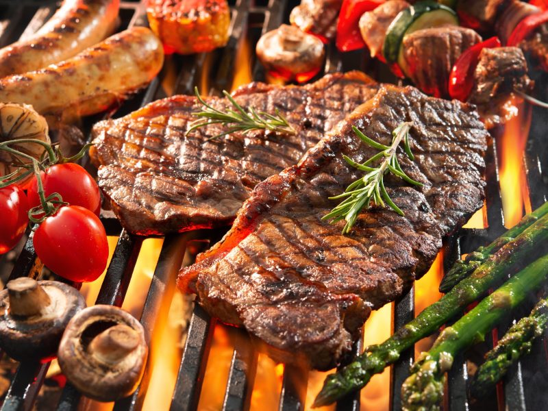 Assorted delicious grilled meat with vegetables sizzling over the coals on barbecue